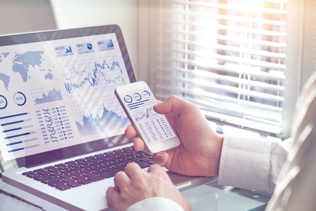 laptop and mobile screens displaying charts and graphs of trend lines and data