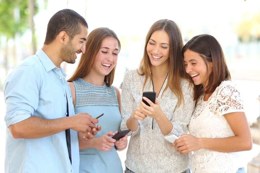 friends looking at a person's phone and laughing