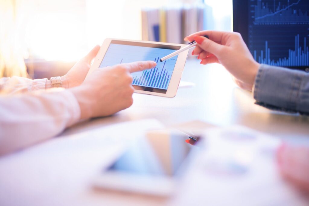 hands pointing to a tablet displaying bar graph results